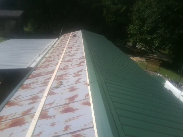Old rusted panels beside newly installed green metal roofing — Wind Damage Roof Repair by Roofing Brothers in Branchville